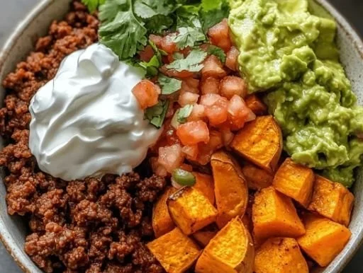 Delicious sweet potato taco bowl topped with fresh vegetables and sauces.